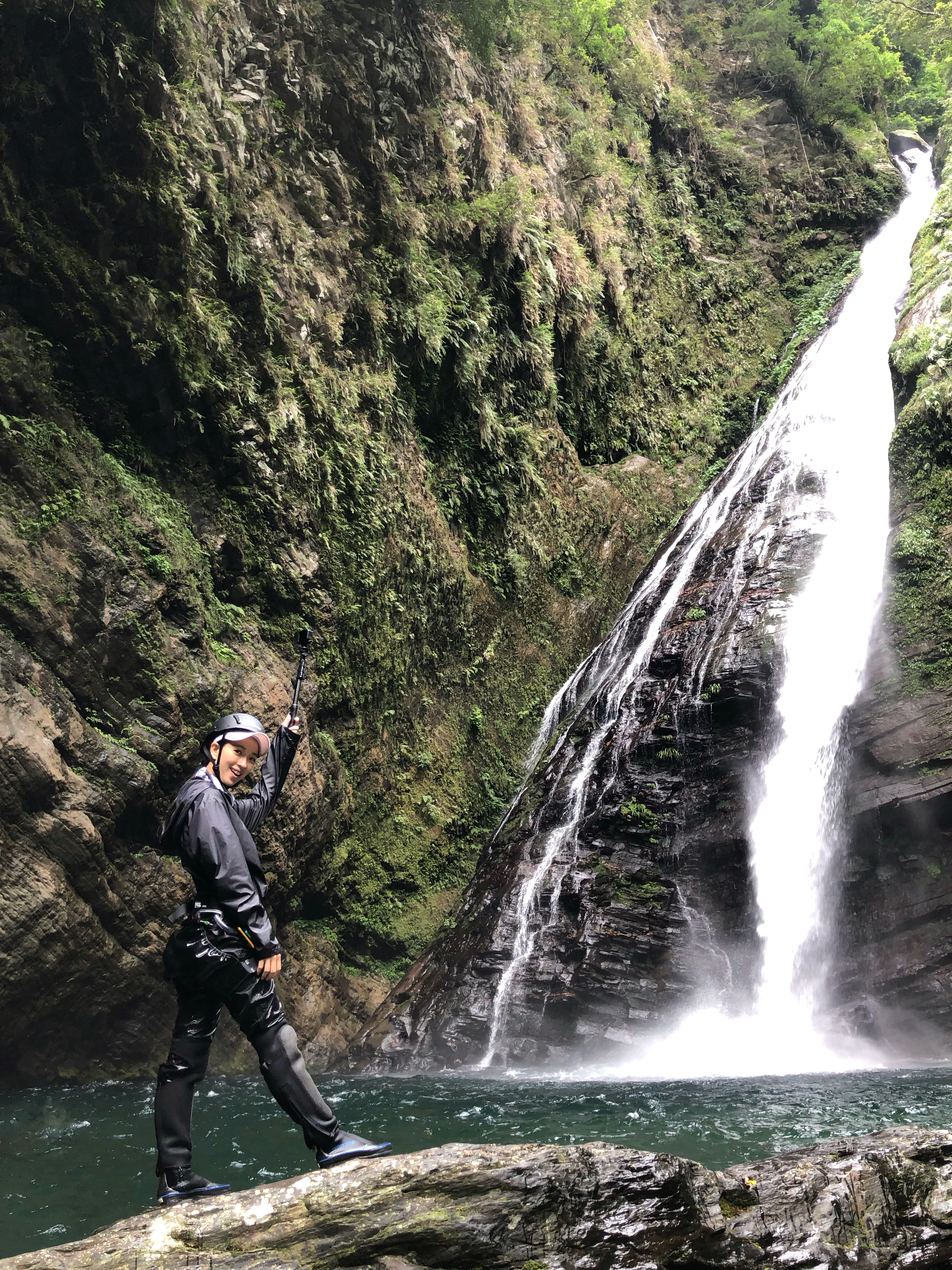 Fan shaped waterfall cascades into deep pool.