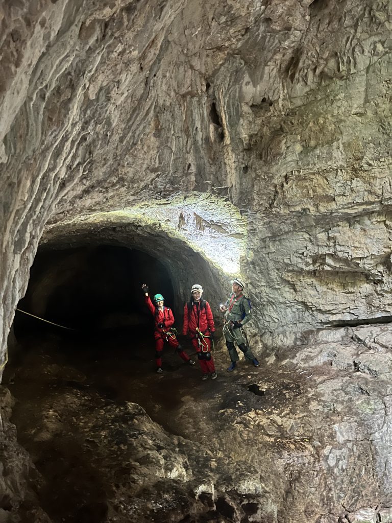 A portrait of three people in a cavern on a caving tour.
