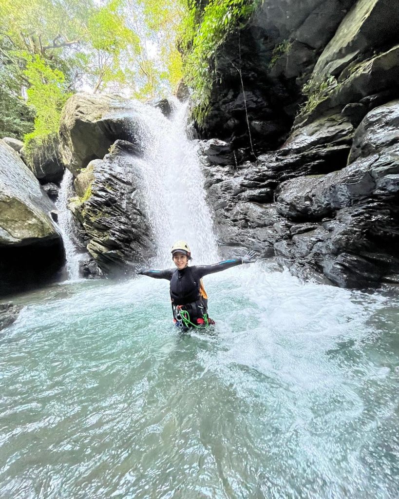 Person below a waterfall smiling.